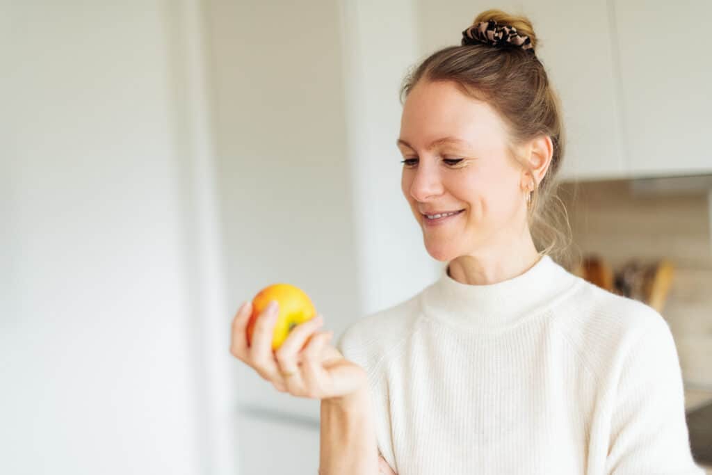 Astrid Nöhring Hormoncoach für Frauen hält einen Apfel