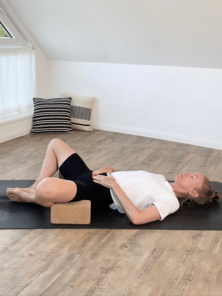 Blonde Frau entspannt in Yogakleidung auf schwarzer Yogamatte