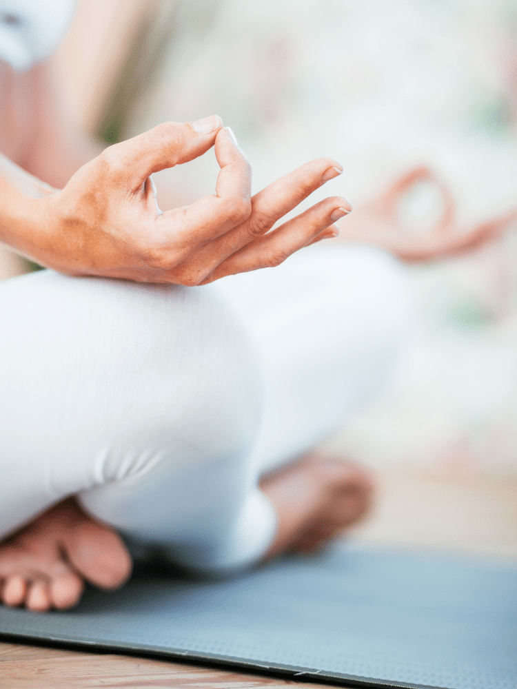 Frau in weißer Leggings meditiert mit einer bestimmten Handgeste